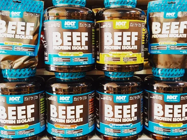 Rows of NXT beef protein isolate tubs and bags in different flavours