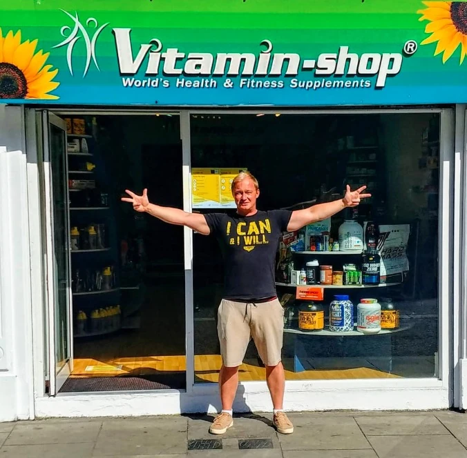 The shop owner standing outside the Vitamin Shop shopfront on Aungier Street with his arms stretched wide